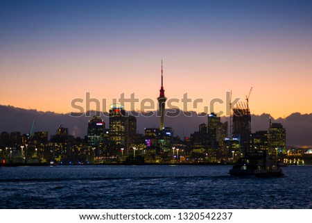 Auckland city skyline at night with city center and Auckland Sky Tower, the iconic landmark of Auckland, New Zealand, The city is waking and Sky Tower is illuminated, Low key lighting picture.