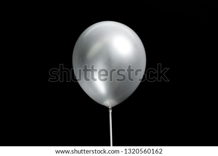 Silver balloon on black dark background. Celebration concept. Flat lay, top view, copy space