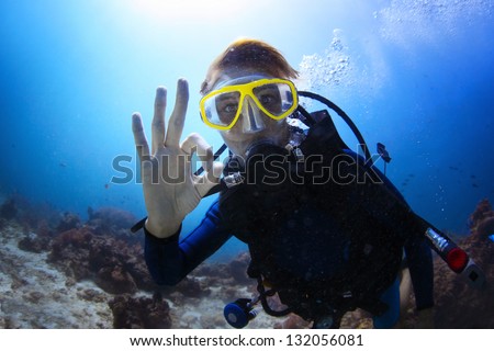 Underwater shoot of a woman diving with scuba and showing ok signal
