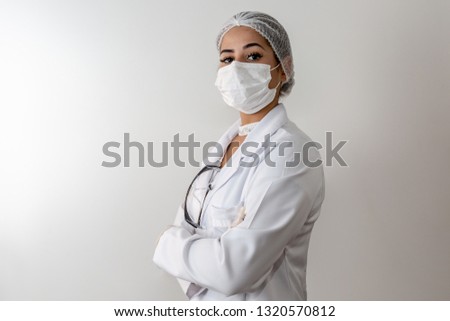 Beautiful young doctor woman in medical white coat and a protective mask and rubber gloves. Isolated over grey background. Copy space for text