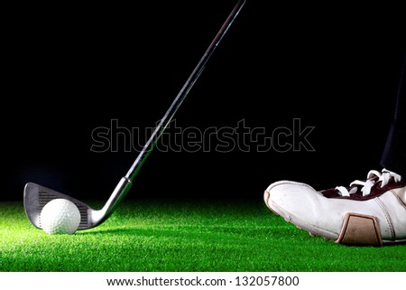 man ready to hit golf ball with golf iron on black background