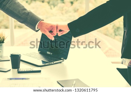 A close up image of fist bump. Hands of young people show strength teamwork over labtop office meeting room,team concept. Group of businesspeople ready for start up outsoutstanding project.