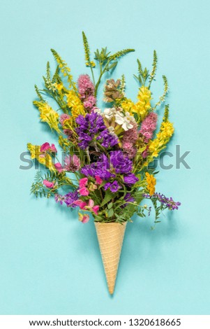 Bouquet field colored flowers in waffle ice cream cone on blue paper background Creative Flat Lay Top view Mock up Concept Women's day or Mothers Day, Hello summer