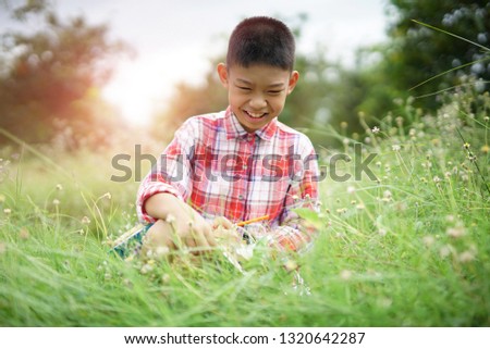 Happy boy sitting on the green grass with picture drawing at park. 
boy writing books.
                          