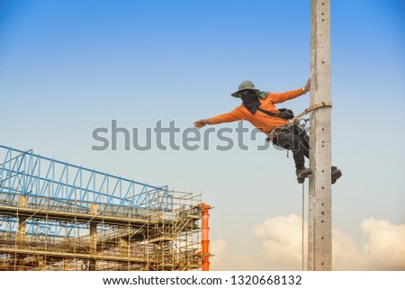 Worker on the high Electrician climbing poles, wear equipment protective safety harness with scaffold on structure site project background.