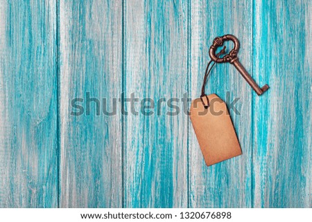 Concept of new life, dream or house with vintage key and mock up empty paper tag on blue wooden background with copy space