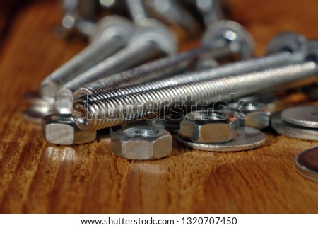 Several long screws for home workshop on a wooden surface closeup. Shallow depth of field