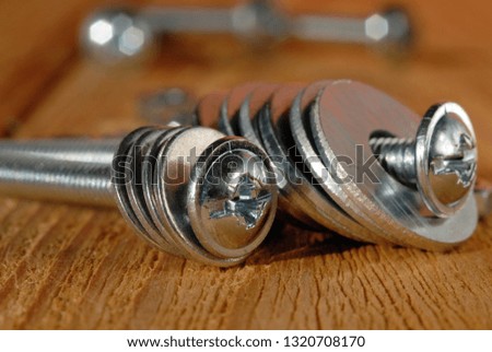 Screws with washers for home workshop on a wooden surface closeup. Shallow depth of field