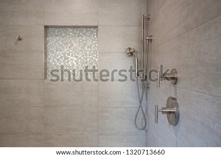 Modern shower with gray tiles, built-in seat and recessed shampoo holder Royalty-Free Stock Photo #1320713660