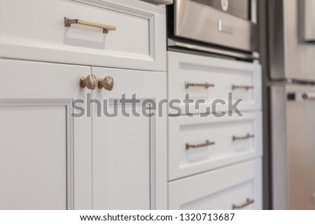 White kitchen built with shaker style cabinets. Shows cabinet details and brushed gold hardware knobs and pulls Royalty-Free Stock Photo #1320713687