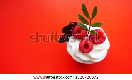 Handmade Sweet dessert, cupcake with butter cream and raspberry on red background