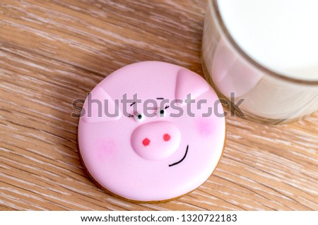 Cookie with little pig symbol and cup of the milk
