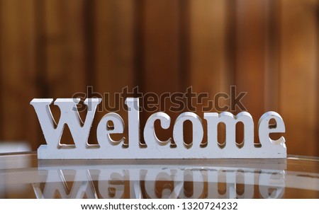 White wooden "Welcome" sign closeup on blur wood background