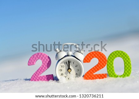 Number 2020 and alarm clock in snow. Happy New Year concept.