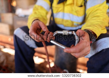 Rope access miner male hand inspecting screw gate Karabiner ensure is clipping correctly into barrel knot and safe good condition prior to use construction mine site Perth, Australia 
