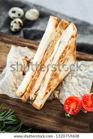 Chicken sandwich with cheese and tomatoes on a wooden board