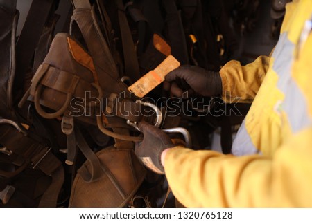 Rope access hand wearing a glove inspecting abseiling safety harness tag label information prior to use construction mine site, Perth, Australia