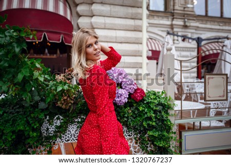 A beautiful young blonde woman in a pretty short red dress walks in the center of Moscow. The central places of the city. The idea and concept of freelancing and free time, while 
