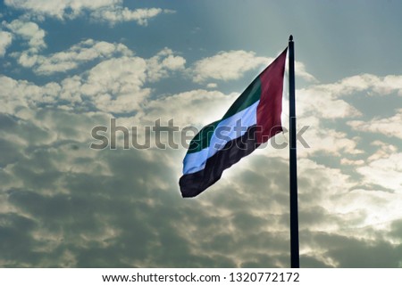 UAE National Flag waving in air with clouds background during sunset at winter