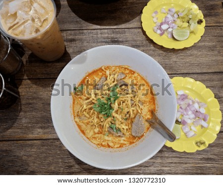 Khao soi traditional Thai food,curry soup with beef on the wood table ,top view 