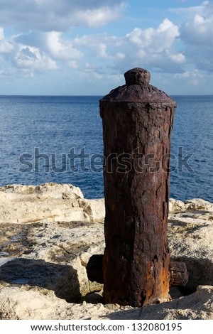 The old stump from the Second War on the rock close to the new Breakwater bridge, at the entrance to Grand Harbour,Malta with the blue sea and cloudy sky background,maltese war stump, symbols close up