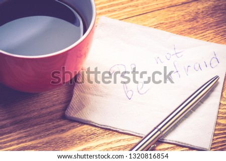 Coffee cup pen and napkin with words on wooden table
