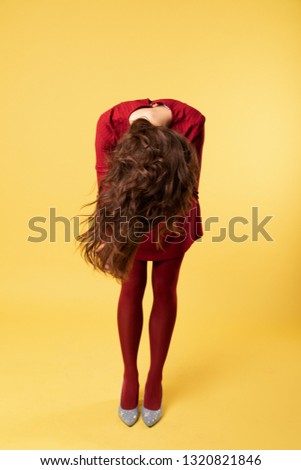 Girl dressed in red dress on yellow background