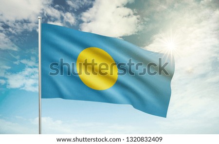 Palau flag waving in the wind against a blue sky and clouds
