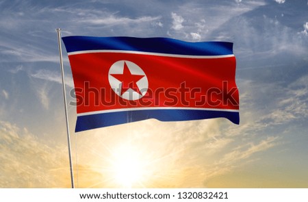 North Korea flag waving in the wind against a blue sky and clouds