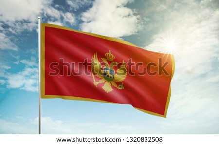 Montenegro flag 2 waving in the wind against a blue sky and clouds