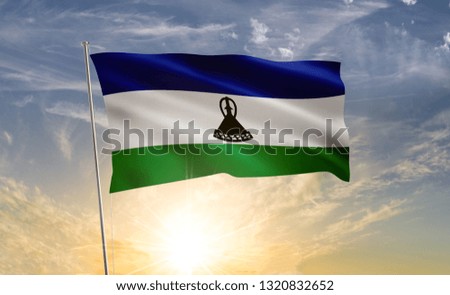 Lesotho flag 2 waving in the wind against a blue sky and clouds