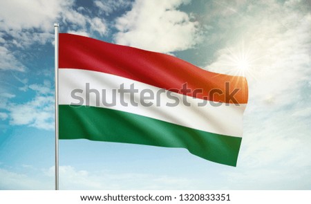 Hungary flag 2 waving in the wind against a blue sky and clouds