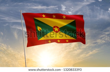 Grenada flag 2 waving in the wind against a blue sky and clouds