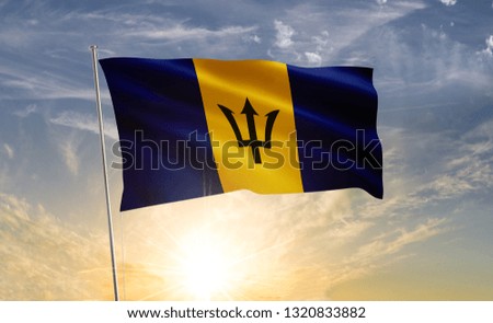 Barbados flag waving in the wind against a blue sky and clouds