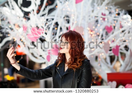 Stylish lady making selfie in the mall. Girl making photo near the Valentine's Day scenery