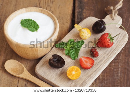 Natural homemade plain organic yogurt mixed with fresh berry fruit white bowl and wood spoon on wood texture background, copy space