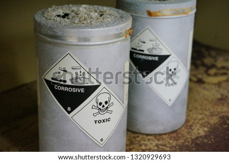 Metal container of hazardous dangerous chemical with very toxic warning symbol, corrosive symbol and effected of its reactivity.