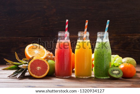 bottles of fruit juice and smoothie with fresh fruits on wooden table Royalty-Free Stock Photo #1320934127