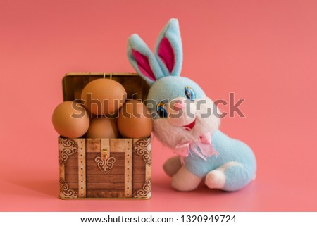 eggs in a chest and easter bunny. Easter concept on pink background