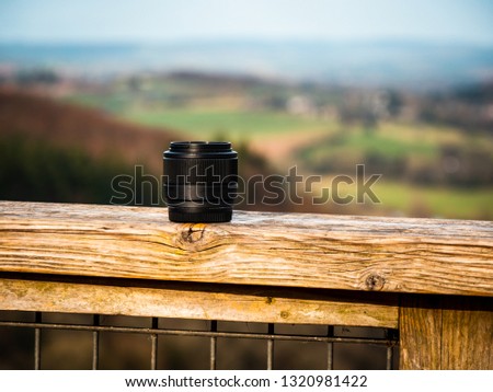 Camera Lens placed on a ledge overlooking a river in Herefordshire. Attractive advert for outdoor photography. 