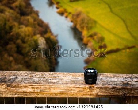 Camera Lens placed on a ledge overlooking a river in Herefordshire. Attractive advert for outdoor photography. 