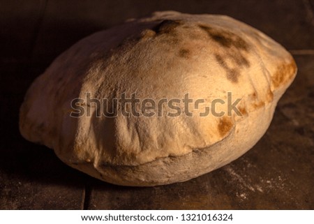 A close-up of Turkish bread baked in a stone oven. When cooked, it stays hollow from the inside.