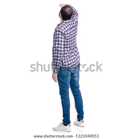A man in jeans and shirt looks into the distance on a white background. Isolation, back view