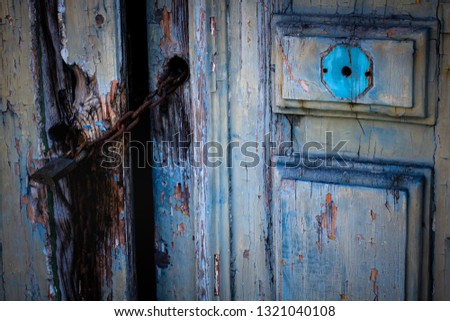 
the picture shows a very old wooden door that began to disintegrate. The door is locked and has blue details in its own right. They are located on the island of Malta