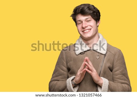 Young handsome man wearing winter coat over isolated background Hands together and fingers crossed smiling relaxed and cheerful. Success and optimistic