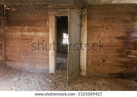 Abandoned farmhouse with wood paneled wall and open grey door deep rural in the south Royalty-Free Stock Photo #1321069427