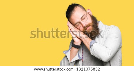Young blond man wearing glasses sleeping tired dreaming and posing with hands together while smiling with closed eyes.