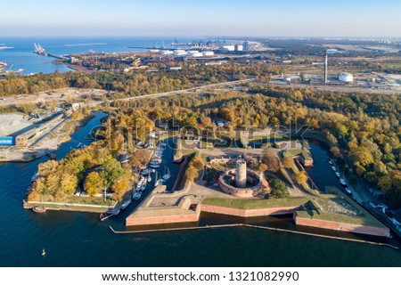 Medieval Wisloujscie Fortress with old lighthouse tower in port of Gdansk, Poland. A unique monument of the fortification works. Aerial view at sunset. Exterior Northern Gdansk port in the background

