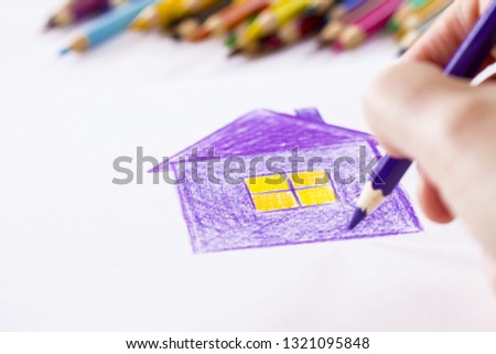 color pencil in hand close-up. drawing at home with colored pencils. drawing house.