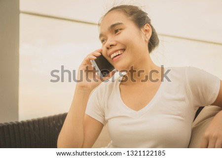 closeup of beautiful young business Asian woman with smartphone use talking texting messenger with skyscrapers in the background, sunshine